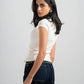Woman wearing a white top and dark jeans on a plain background