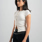 Woman wearing a white blouse with a black belt against a plain background
