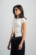 Woman wearing a white blouse with a black belt against a plain background