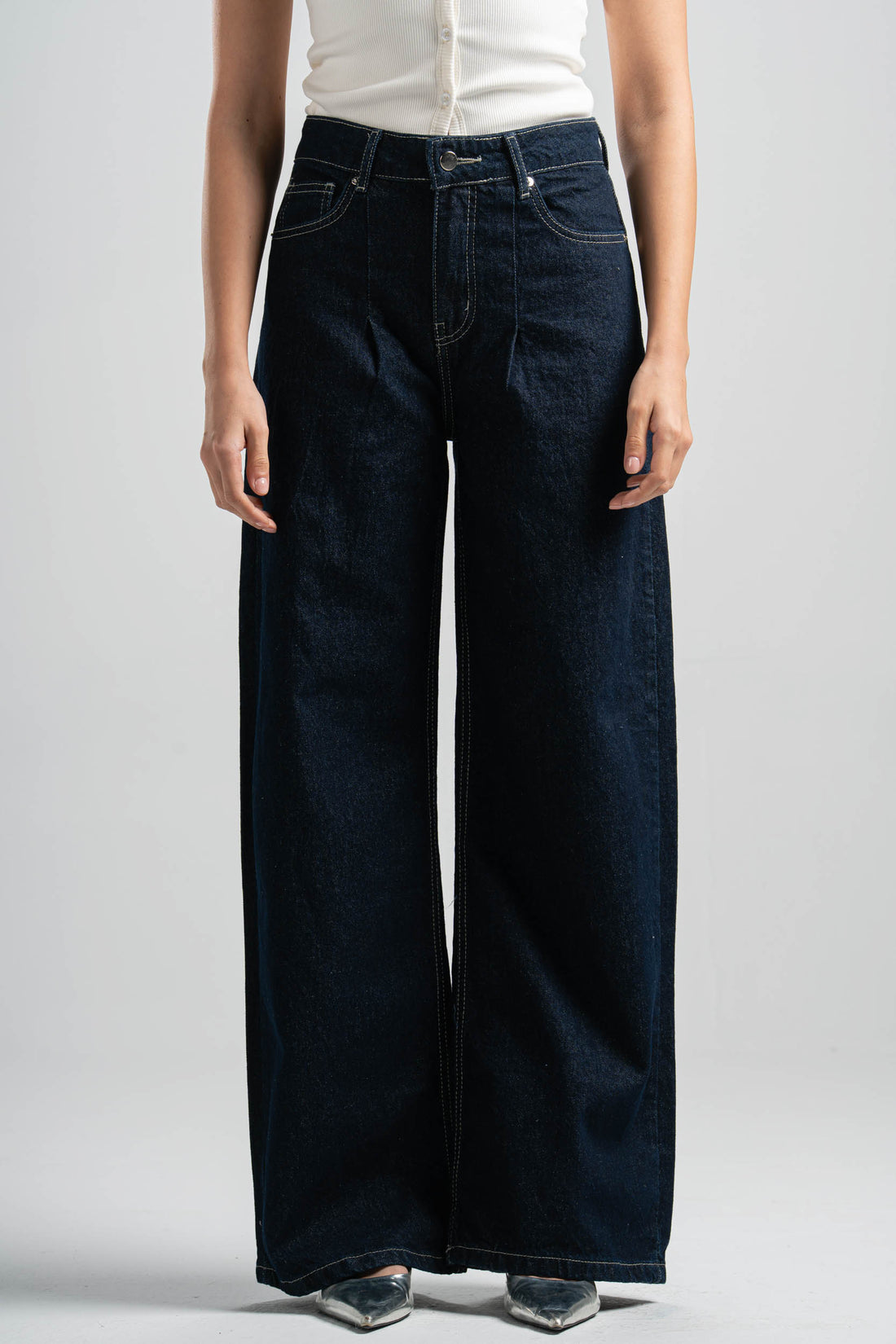 Person wearing dark blue wide-leg jeans on a plain background
