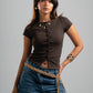 Woman wearing a brown top and blue jeans with a gray background