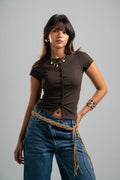 Woman wearing a brown top and blue jeans with a gray background