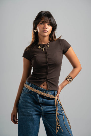 Woman wearing a brown top and blue jeans with a gray background