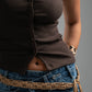 Person wearing a brown shirt and blue jeans with a braided belt on a gray background
