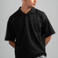 Man wearing a black polo shirt against a gray background