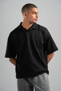 Man wearing a black polo shirt against a gray background