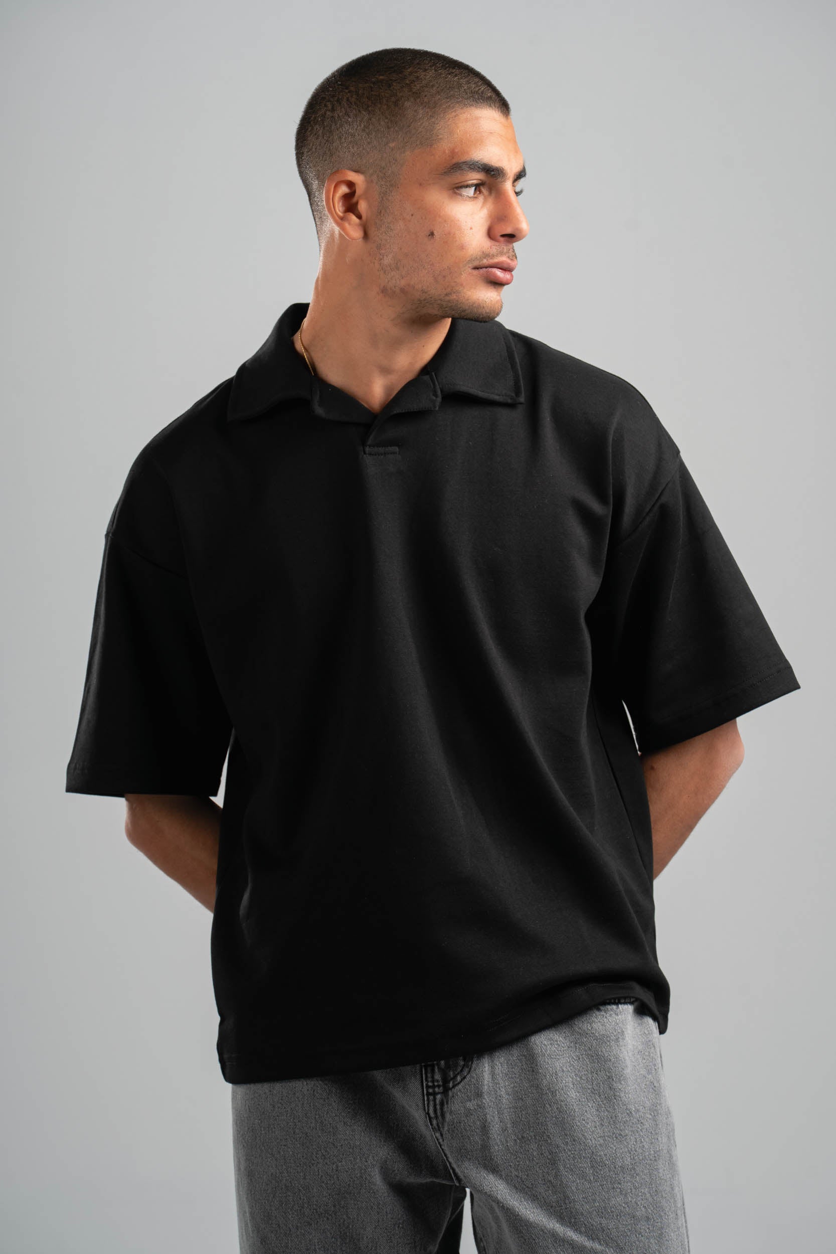 Man wearing a black polo shirt against a gray background