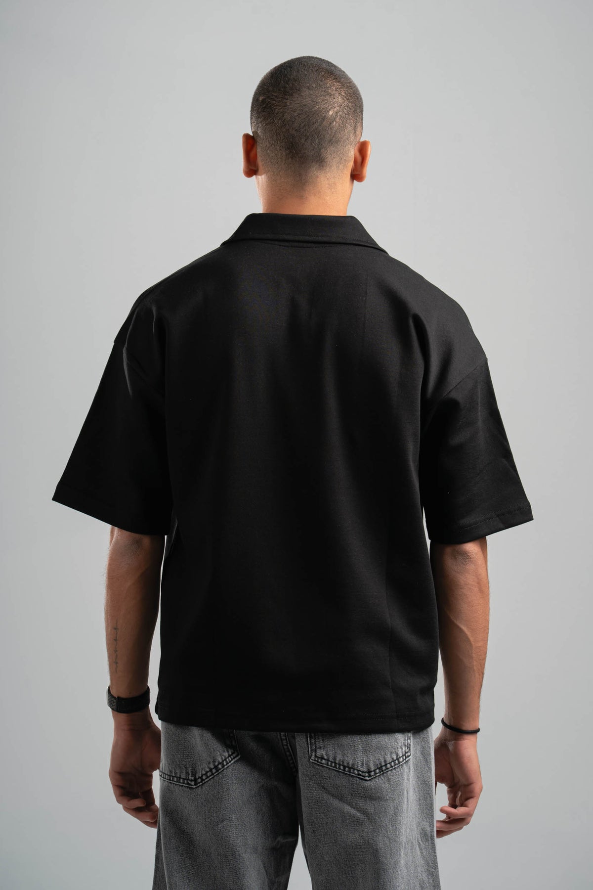 Person wearing a black polo shirt on a gray background