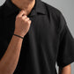 Man wearing a black polo shirt against a gray background