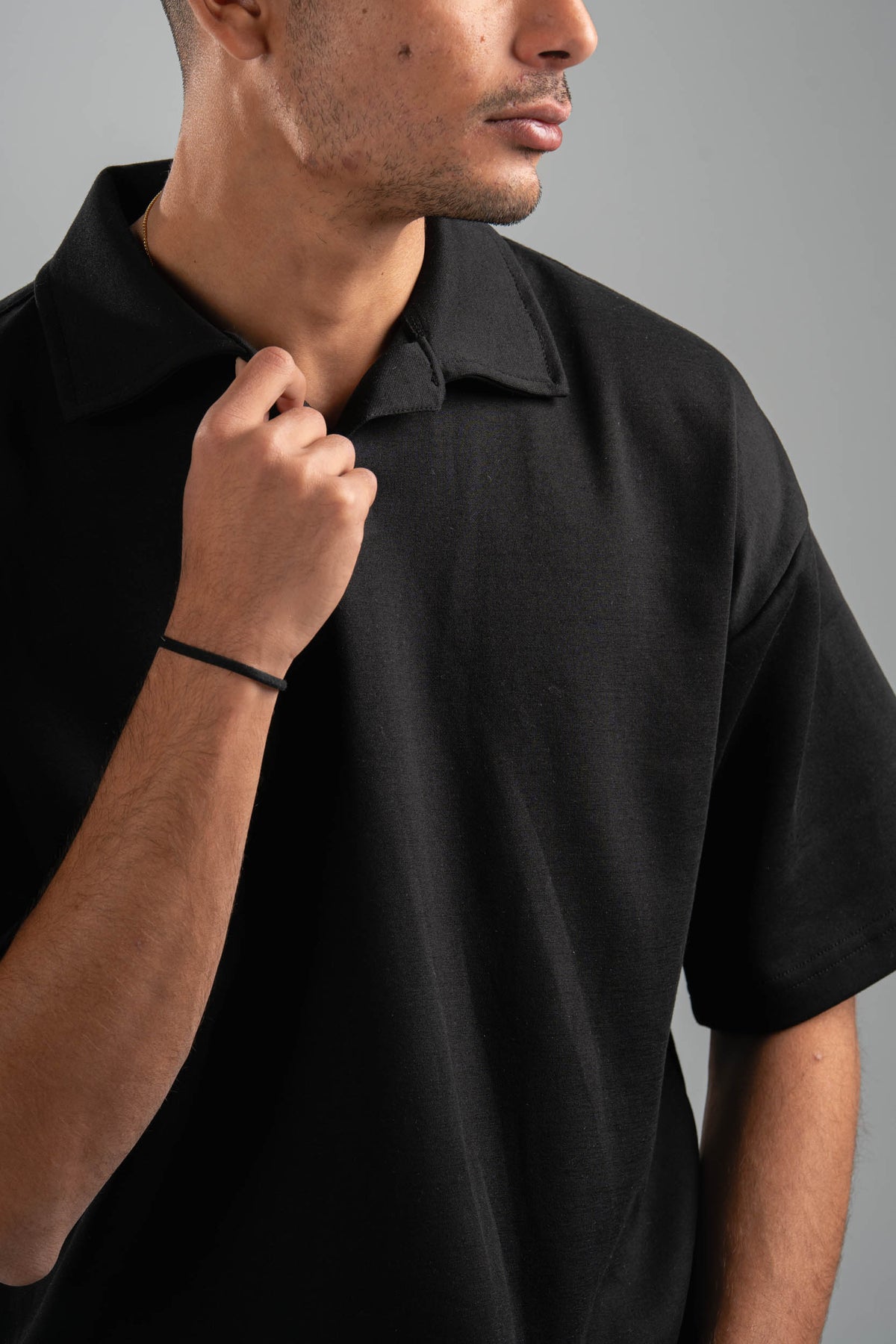Man wearing a black polo shirt against a gray background