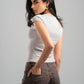 Woman wearing a white t-shirt and brown pants against a gray background