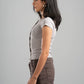Woman wearing a gray t-shirt and brown pants against a gray background