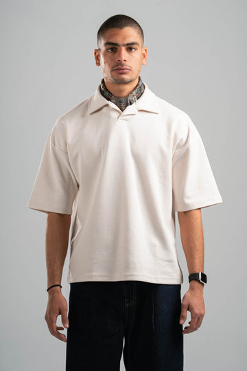 Man wearing a beige short-sleeve shirt and dark pants on a gray background