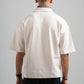 Person wearing a beige short-sleeve shirt on a gray background