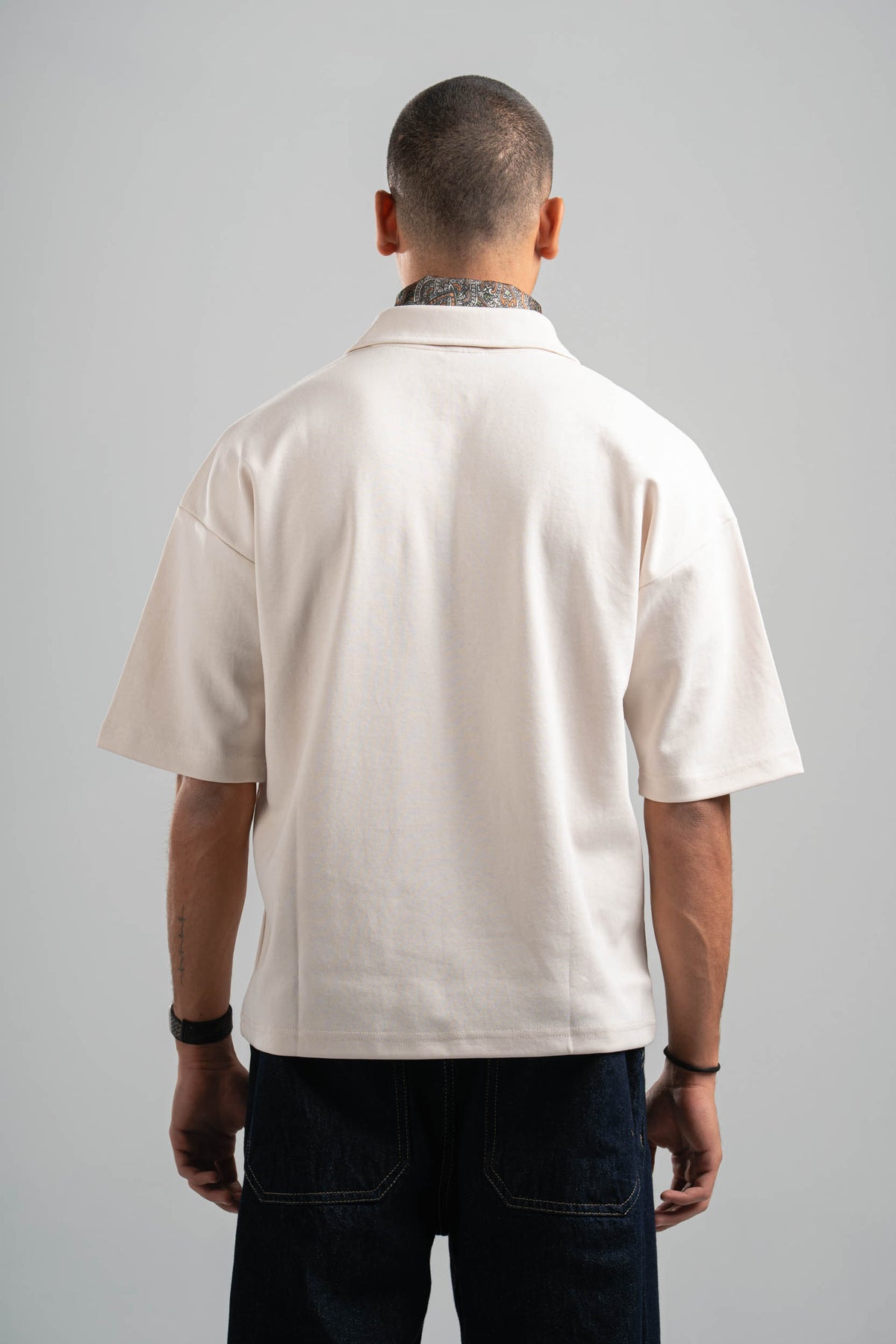 Person wearing a beige short-sleeve shirt on a gray background