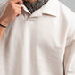 Person wearing a white shirt with a patterned scarf around their neck against a gray background