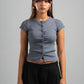 Woman wearing a gray short-sleeve top and black pants against a gray background