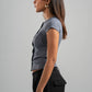 Woman wearing a gray top and black pants against a gray background