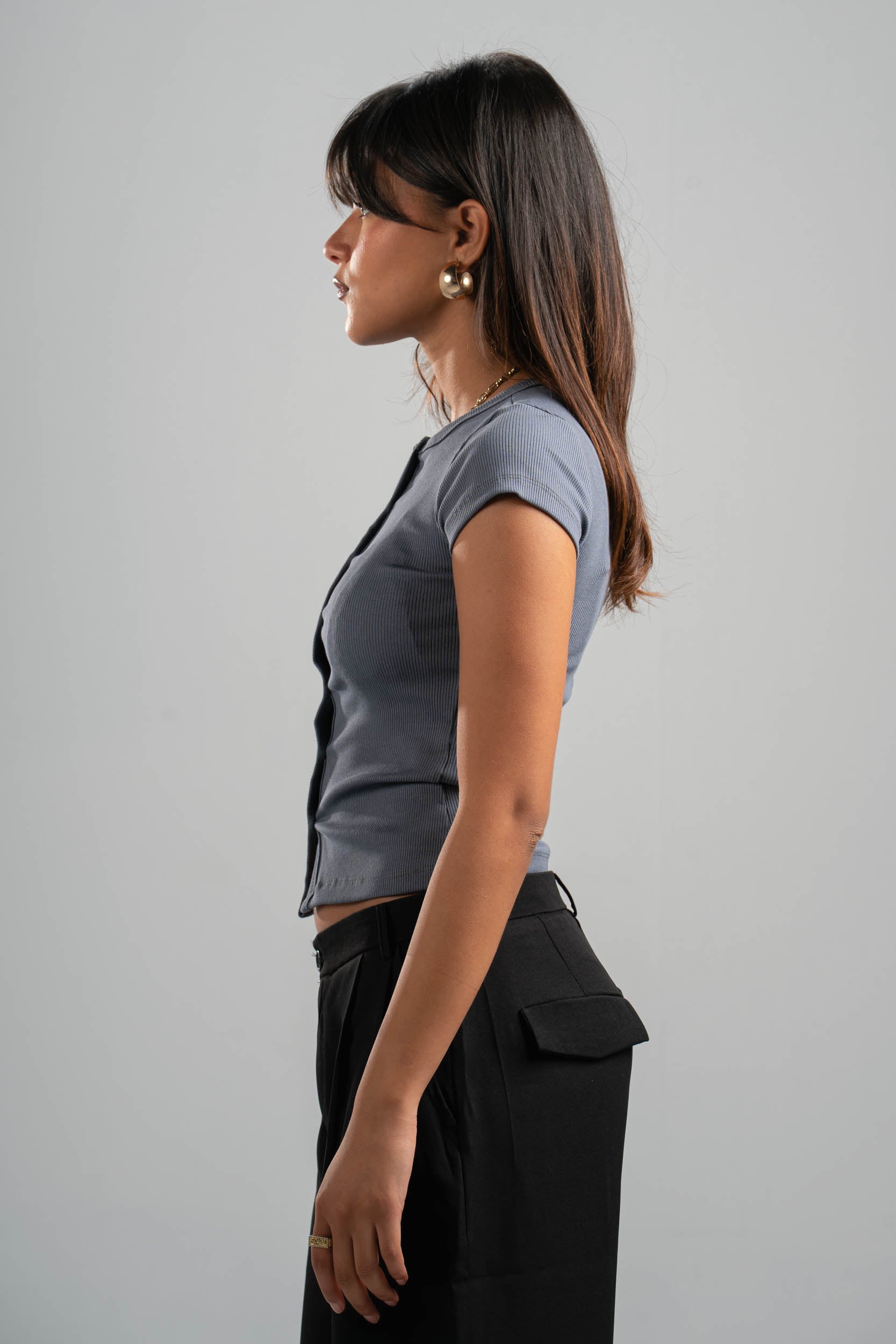 Woman wearing a gray top and black pants against a gray background
