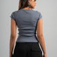 Woman wearing a gray top and black pants against a gray background
