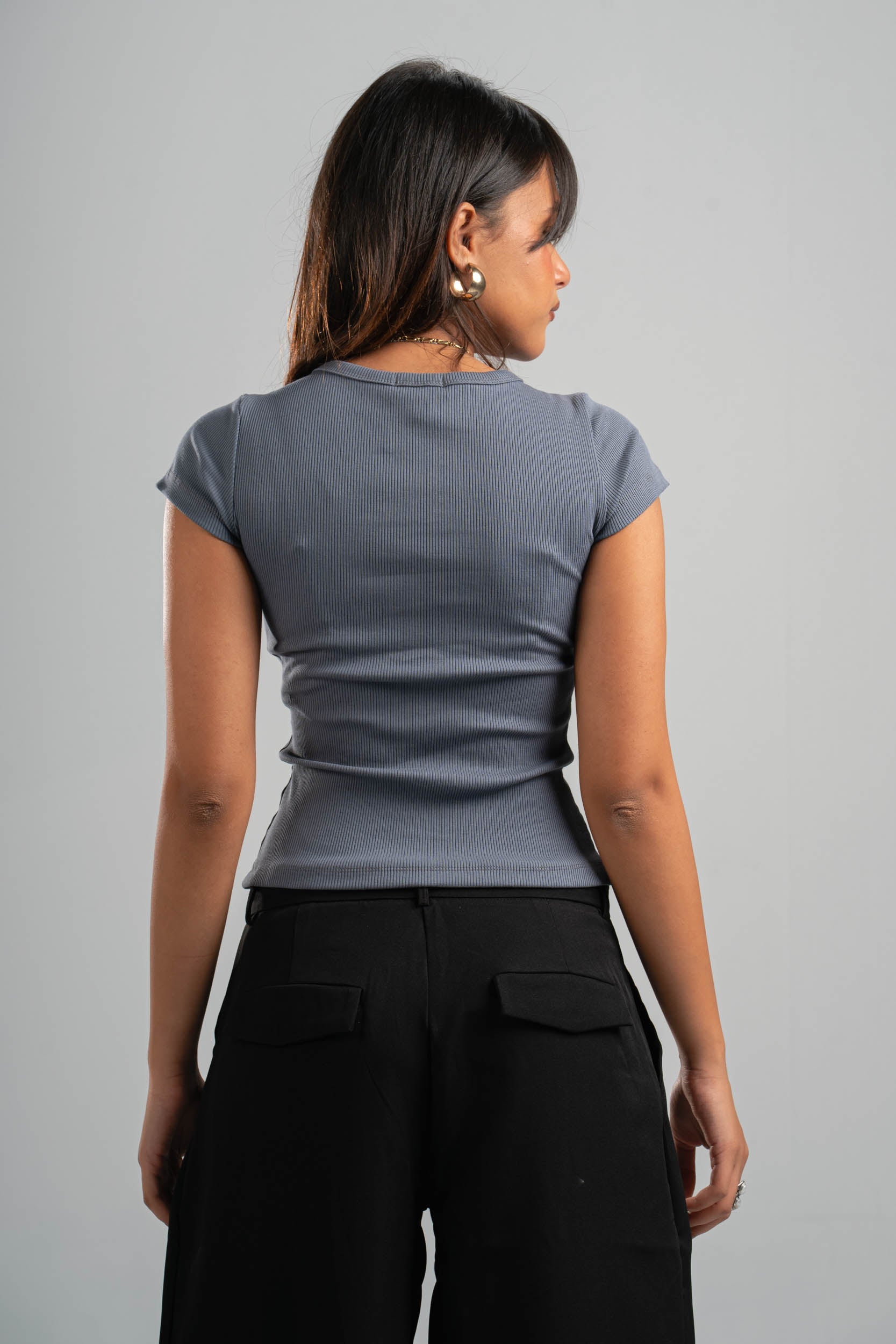 Woman wearing a gray top and black pants against a gray background