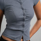 Person wearing a gray ribbed top with buttons on a plain background