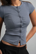 Person wearing a gray ribbed top with buttons on a plain background