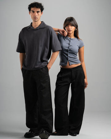 Two people wearing matching black and gray outfits on a gray background