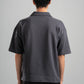 Person wearing a gray polo shirt from behind on a plain background