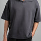Person wearing a dark gray polo shirt against a gray background