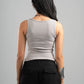 Person wearing a gray sleeveless top and black pants on a gray background