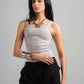 Woman wearing a gray tank top and black pants on a gray background