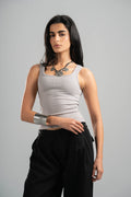 Woman wearing a gray tank top and black pants on a gray background