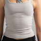Person wearing a gray tank top and black pants with a neutral background