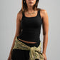 Woman wearing a black tank top and green scarf on a gray background