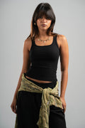 Woman wearing a black tank top and green scarf on a gray background