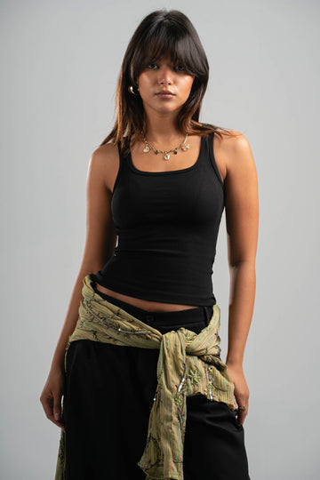Woman wearing a black tank top and green scarf on a gray background