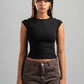 Woman wearing a black top and brown pants against a gray background