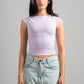 Woman wearing a light purple sleeveless top and light blue jeans against a gray background