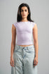 Woman wearing a light purple sleeveless top and light blue jeans against a gray background