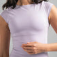 Woman wearing a light purple crop top and denim shorts against a gray background