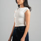 Woman wearing a white sleeveless top and dark jeans on a gray background