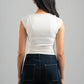 Person wearing a white top and dark jeans against a gray background