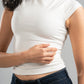 Person wearing a white crop top and dark jeans against a gray background