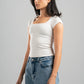 Woman wearing a white t-shirt and blue jeans against a gray background