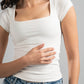 Woman wearing a white t-shirt and blue jeans against a gray background