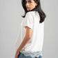 Woman wearing a white t-shirt with lace trim and blue jeans on a gray background