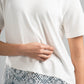 White t-shirt with lace trim worn by a person on a gray background