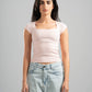 Woman wearing a light pink top and light blue jeans against a gray background