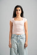 Woman wearing a light pink top and light blue jeans against a gray background